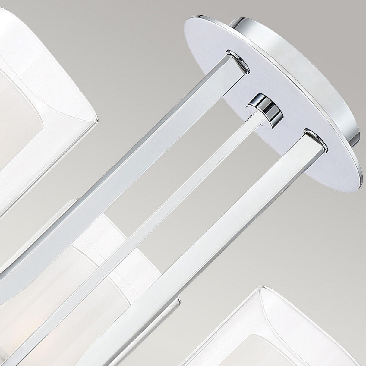 Close-up of the Kolt 3 Light Wall Light in polished chrome, showcasing its modern design with a sleek, dual-glass feature. The fixture comprises polished chrome rods supporting a round metal base with a silver finish, set against a neutral gray background. This light is perfect for enhancing any space with its minimalist charm and elegance.