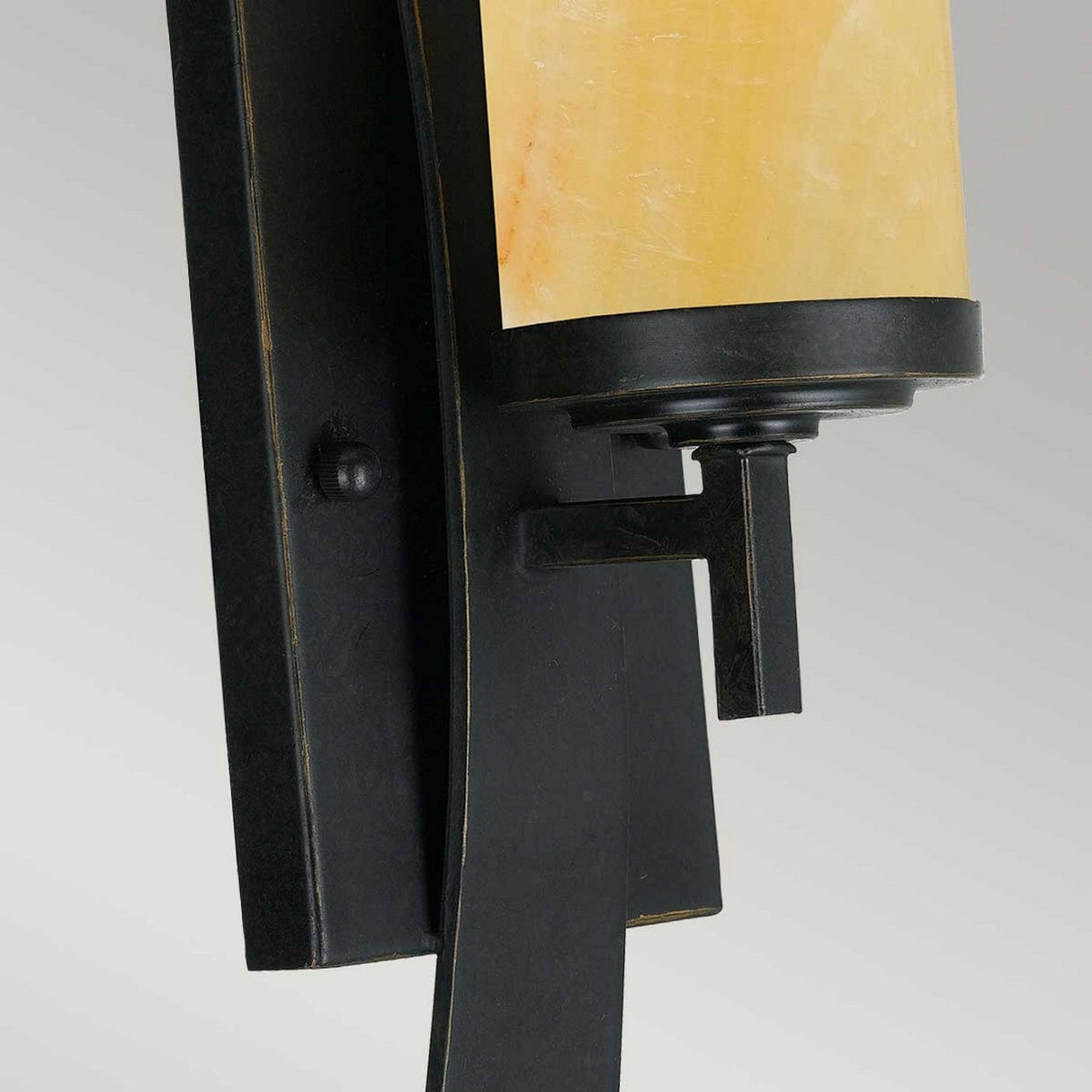 A close-up view of the Kyle 1 Light Wall Light showcases its elegant Imperial Bronze base paired with an onyx shade in a cream hue. Its modern and minimalist design creates a striking contrast against a neutral background.