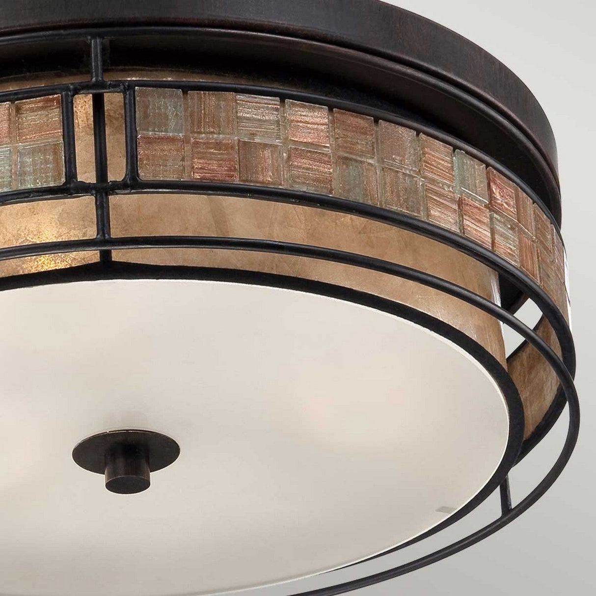Close-up of the Laguna 3 Light Large Flush - Renaissance Copper, a flush mount light fixture showcasing a circular design with mosaic-style detailing in shades of brown and gold along the edge. Constructed from metal and glass, it is mounted on a neutral-colored ceiling.