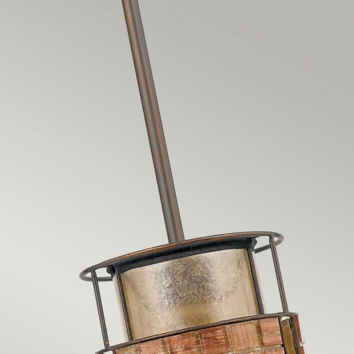 Close-up of the Laguna 1 Light Mini Pendant - Renaissance Copper, showcasing its vintage metal lantern design with a cylindrical body and central vertical rod. Its weathered appearance highlights visible textures and a muted color palette, set against a light gray background.