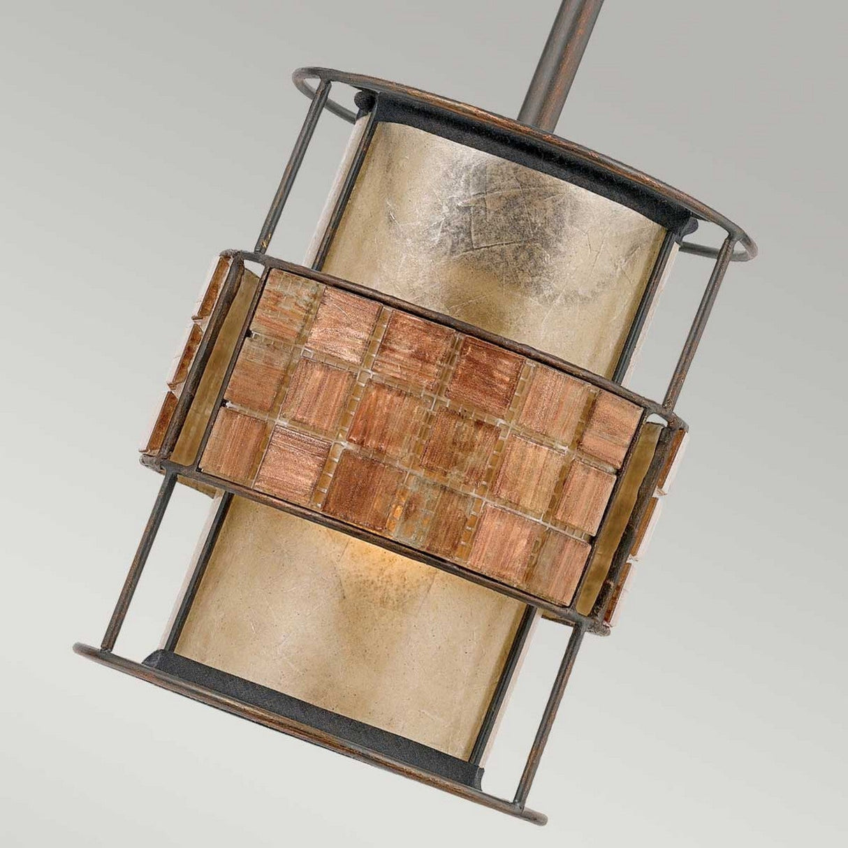 The Laguna 1 Light Mini Pendant - Renaissance Copper showcases a warm golden glow complemented by a textured grid pattern of brownish-orange squares around the center, reminiscent of a mosaic tile stripe. It gracefully hangs from a slender rod against an unobtrusive background.