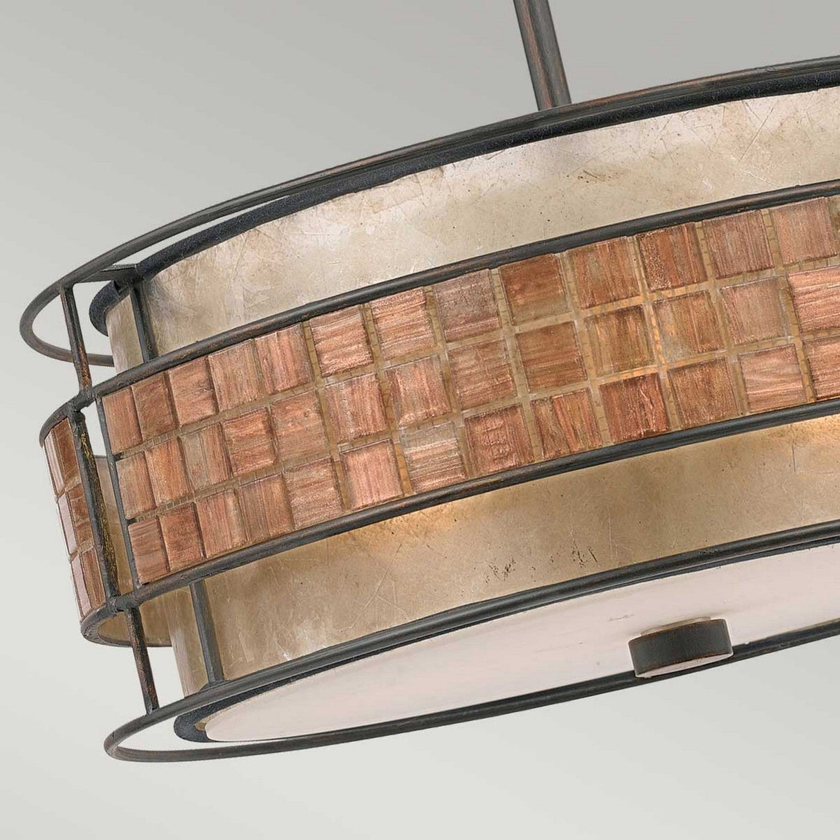 This image shows a close-up of the Laguna 4 Light Chandelier in Renaissance Copper, which boasts a circular design with a metal frame. The outer band is adorned with a mosaic pattern of small brown and beige tiles, complemented by translucent panels behind them, giving the fixture an appealing blend of modern and rustic charm.