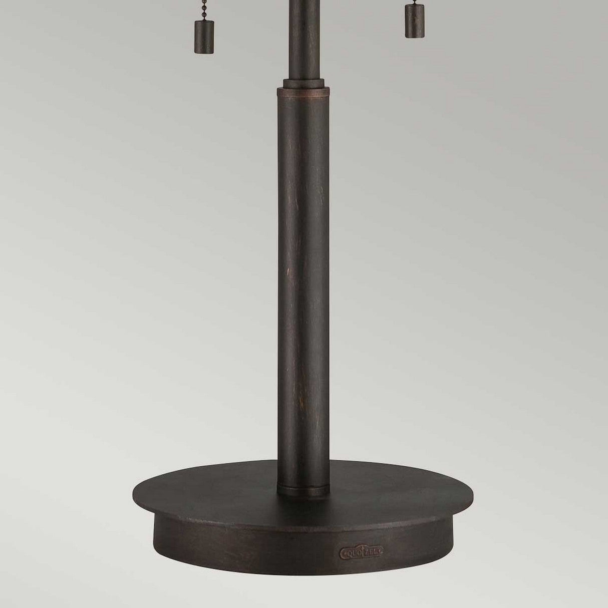 A detailed view of the Laguna 2 Light Table Lamp - Renaissance Copper reveals a dark metallic base featuring a round pedestal and cylindrical pole. Two pull chains hang near the top, enhancing the warm tones of the taupe mica shade set against a neutral gray backdrop.