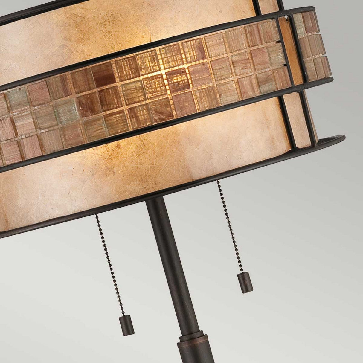 Close-up of the Laguna 2 Light Table Lamp - Renaissance Copper, highlighting its patterned taupe mica shade. The shade displays a mosaic of square tiles in earthy tones, encased in a dark metal frame that evokes Renaissance copper artistry. The lamp is elegantly equipped with two pull chains for easy on and off operation.