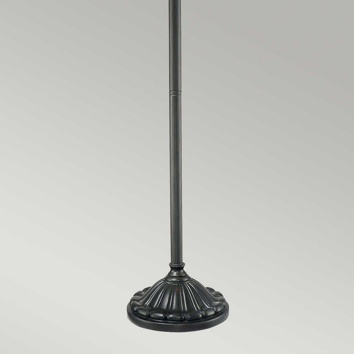 The Larissa 2 Light Tiffany Floor Lamp in Vintage Bronze features a decorative base with a textured finish. The circular base showcases an Art Nouveau-inspired fluted pedestal design, supporting a slender vertical pole against a light gray background.