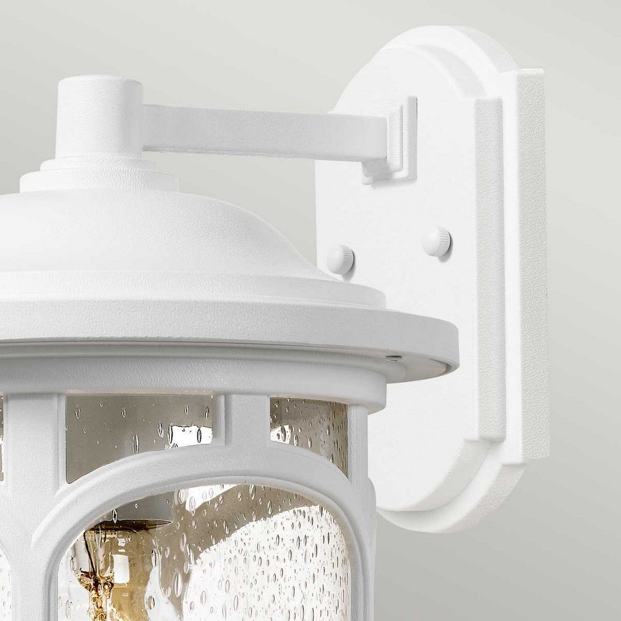 The Marblehead Outdoor 1 Light Medium Wall Lantern in white, featuring a clear seedy glass shade and a visible bulb, is mounted on a rectangular backplate against a light gray wall.