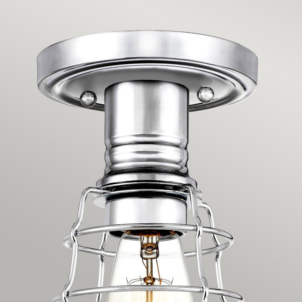 Close-up of the Mixon 1 Light Semi-Flush in polished chrome, featuring an exposed bulb enclosed within a wire cage. The design is both industrial and sleek, set against a light gray background.
