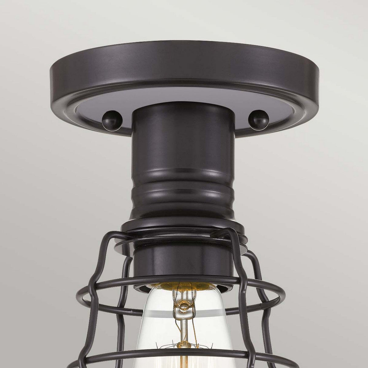 The Mixon 1 Light Semi-Flush in Palladian Bronze exudes industrial appeal with its exposed bulb encased in a metal cage, attached to a round base, and finished with a subtle Palladian Bronze hue.