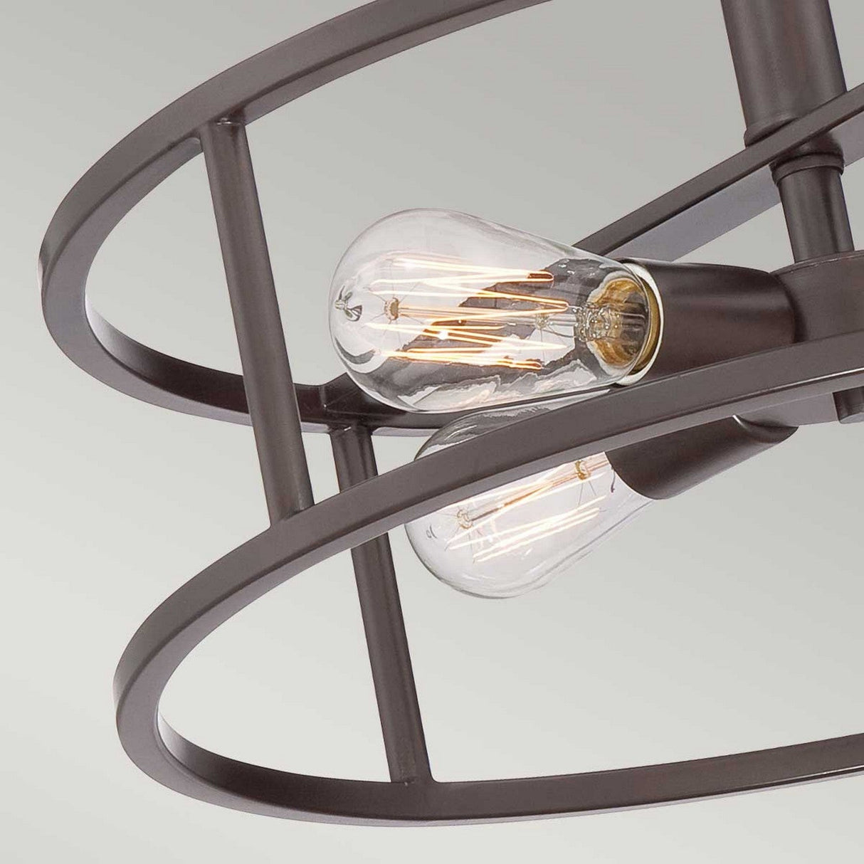 Close-up view of two Victorian Edison-style bulbs in the modern New Harbor 4 Light Semi-Flush fixture, featuring circular designs in a dark metal aesthetic set against a light background. This industrial piece showcases a Western Bronze finish that enhances its timeless appeal.