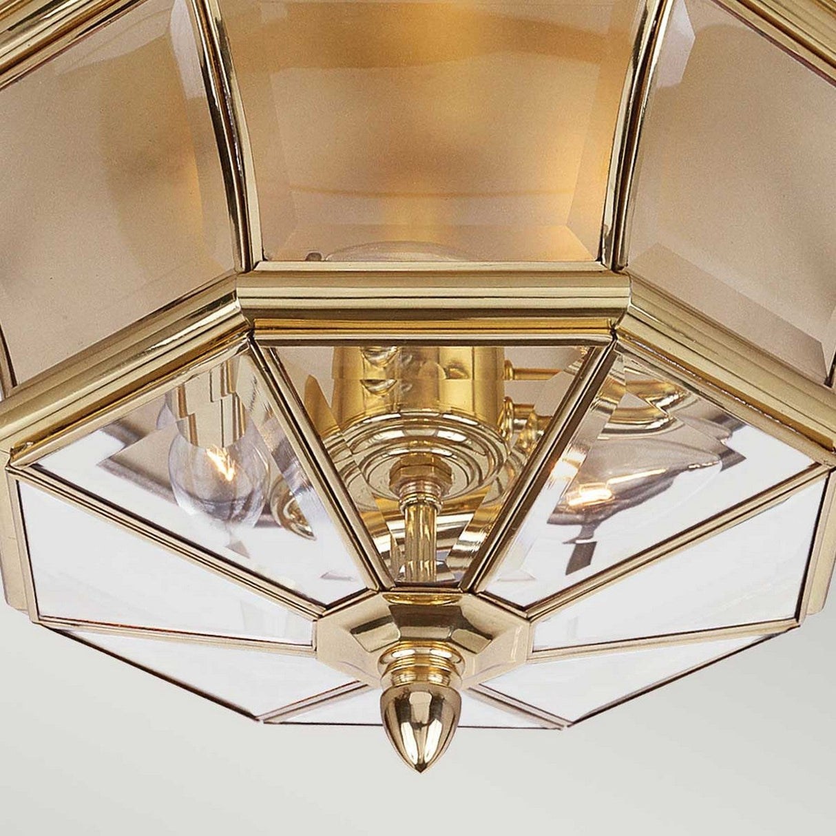 Presenting the Newbury Outdoor 3 Light Flush in Lacquered Polished Brass, this elegant ceiling light features clear beveled glass panels offering a close-up view of exposed bulbs. Its design incorporates geometric shapes and is accented with a central decorative finial, infusing any space with a modern flair.