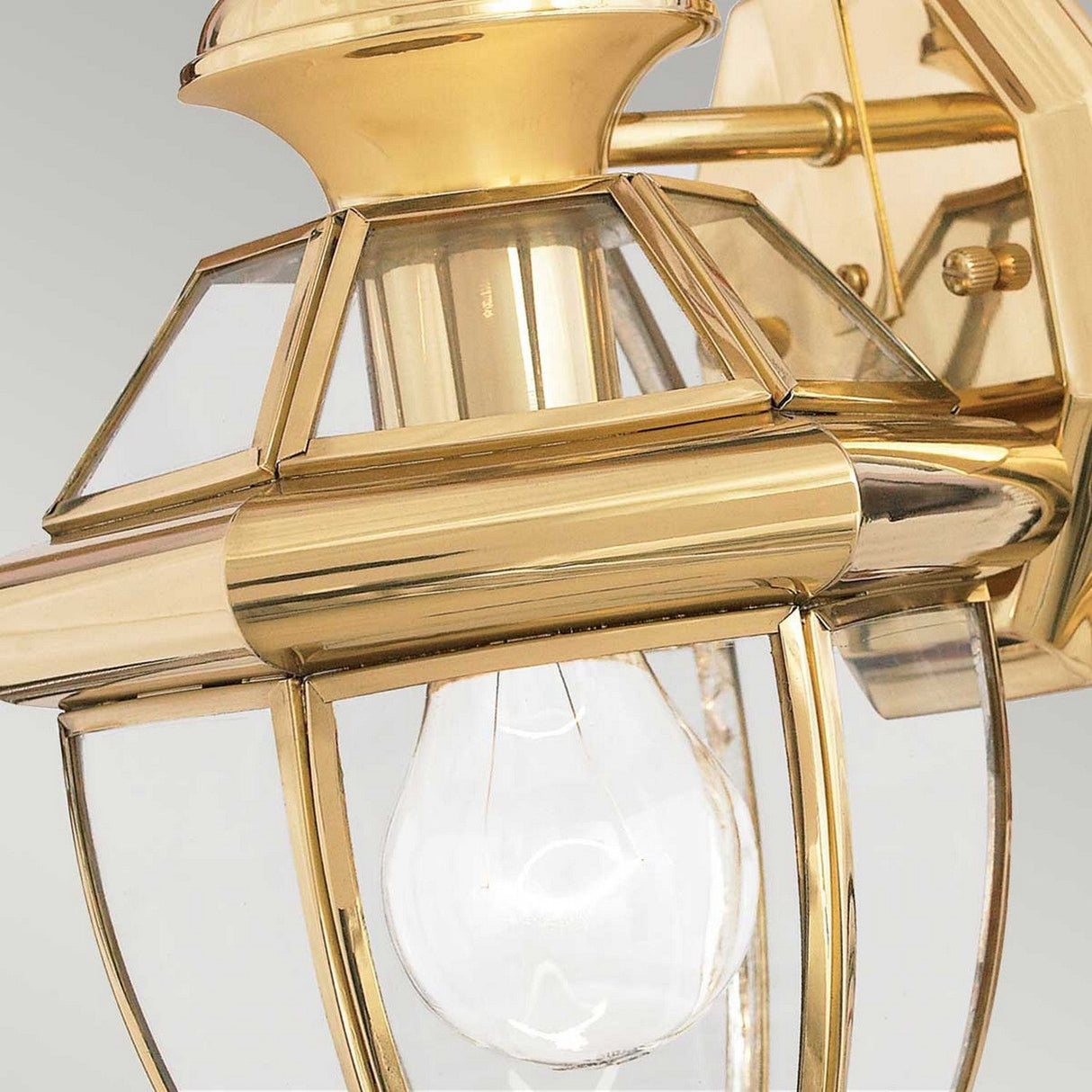 The Newbury Outdoor 1 Light Small Wall Lantern, made of lacquered polished brass, showcases clear beveled glass panels that reveal an exposed light bulb. This hexagonal fixture features a reflective golden finish, enhancing the elegance of any outdoor space.