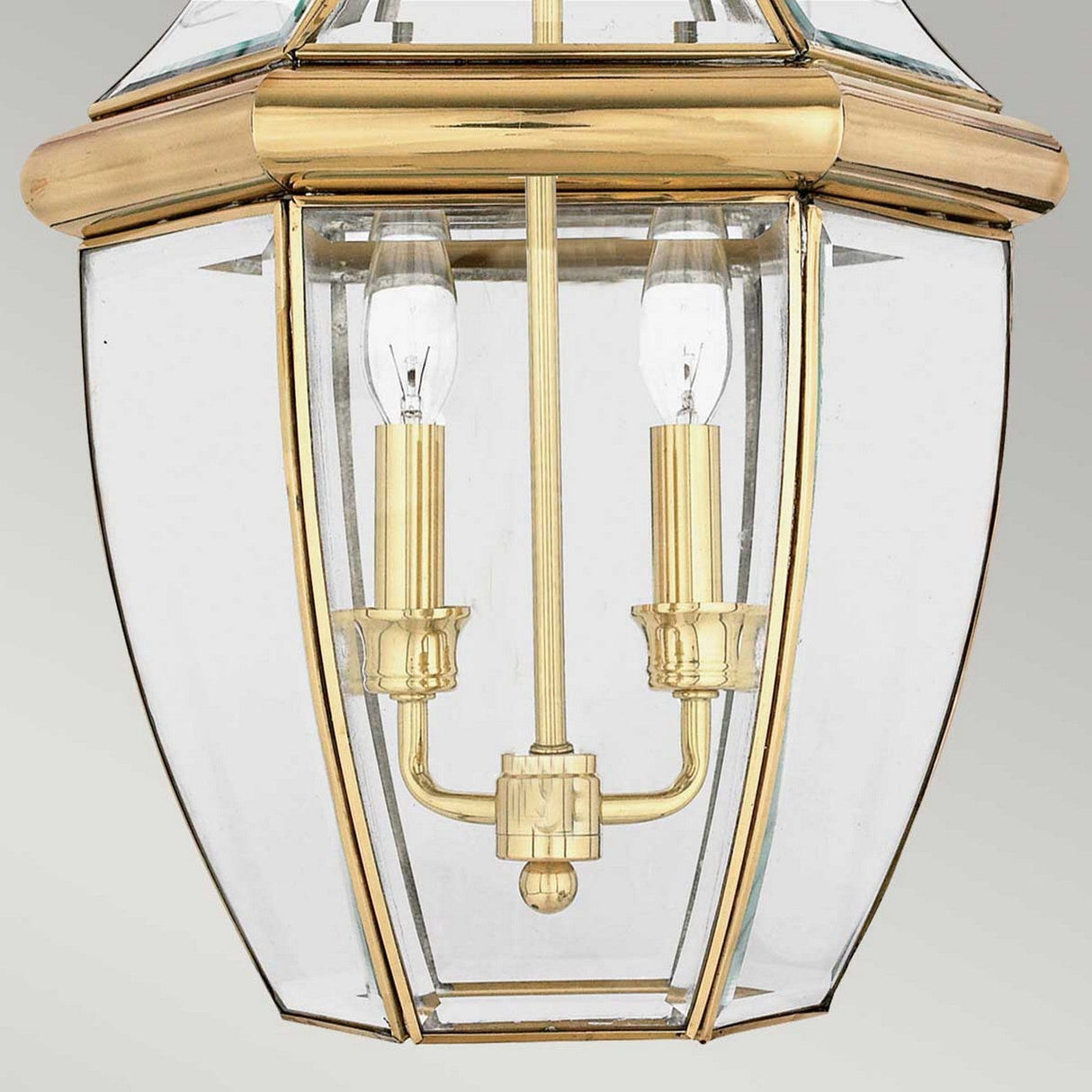 Close-up of the Newbury Outdoor 2 Light Large Chain Pendant in lacquered polished brass, showcasing two candle-shaped bulbs. Its elegant lines and clear beveled glass panels emphasize the classic design, making it an ideal outdoor pendant light that exudes timeless charm.