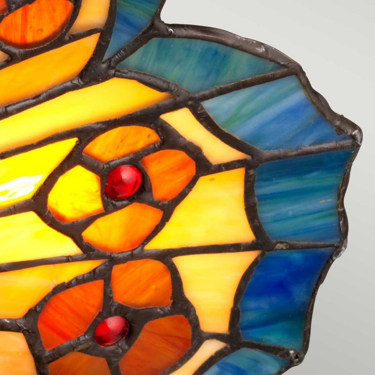 A stained glass design in the Tiffany Animal Lamps collection, showcasing an abstract pattern with sections of orange, yellow, and blue and red circular accents against a gray background, reminiscent of the elegance found in the orange butterfly lamp with architectural bronze fixtures.