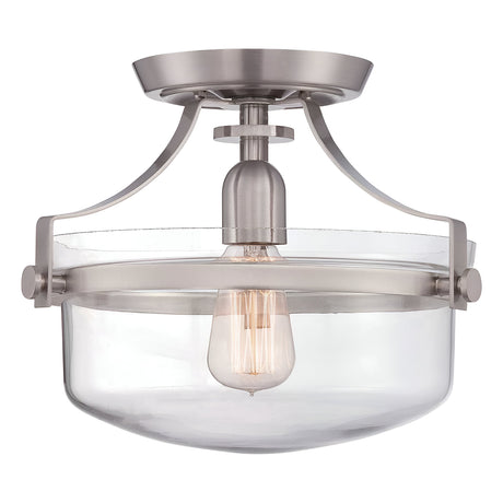 Discover the industrial allure of the Penn Station 1 Light Semi-Flush - Brushed Nickel, a modern ceiling fixture featuring an exposed bulb design, clear glass shade, and circular mounting base that effortlessly combines industrial and contemporary aesthetics.