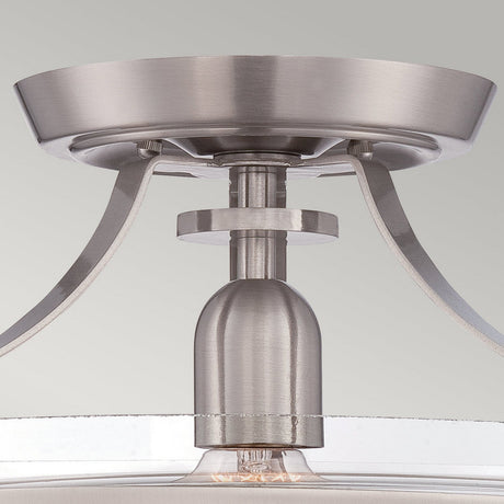The Penn Station 1 Light Semi-Flush in brushed nickel is a sleek and modern light fixture. Its design includes a round canopy with elegantly curved arms connecting to a central bulb holder, exuding industrial charm while showcasing a contemporary and minimalist aesthetic.