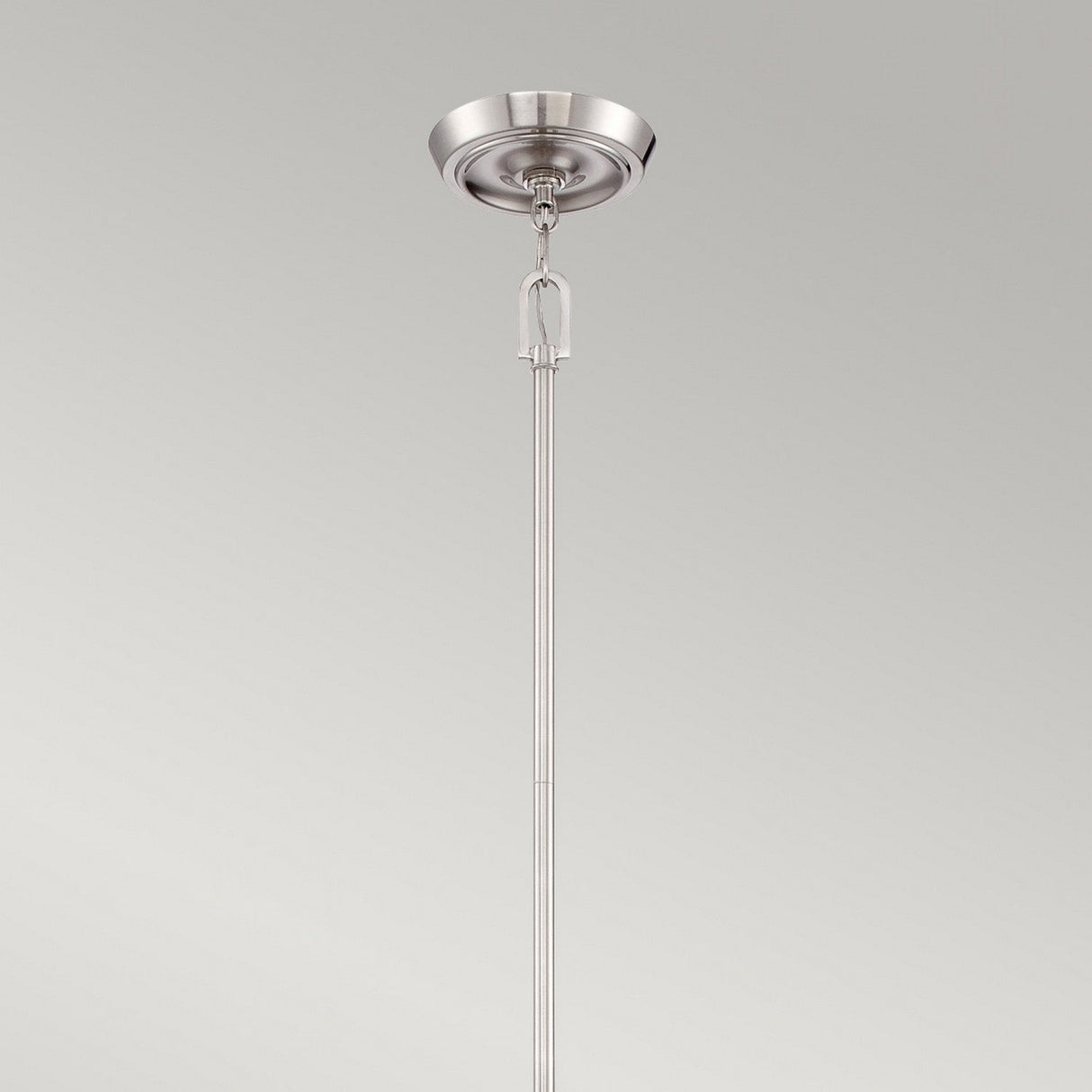 The Penn Station 3 Light Chandelier - Brushed Nickel exudes industrial elegance with its sleek design. It boasts a brushed nickel finish and features a smooth, slender rod extending from a circular ceiling plate, offering a modern twist in lighting design against a plain background.