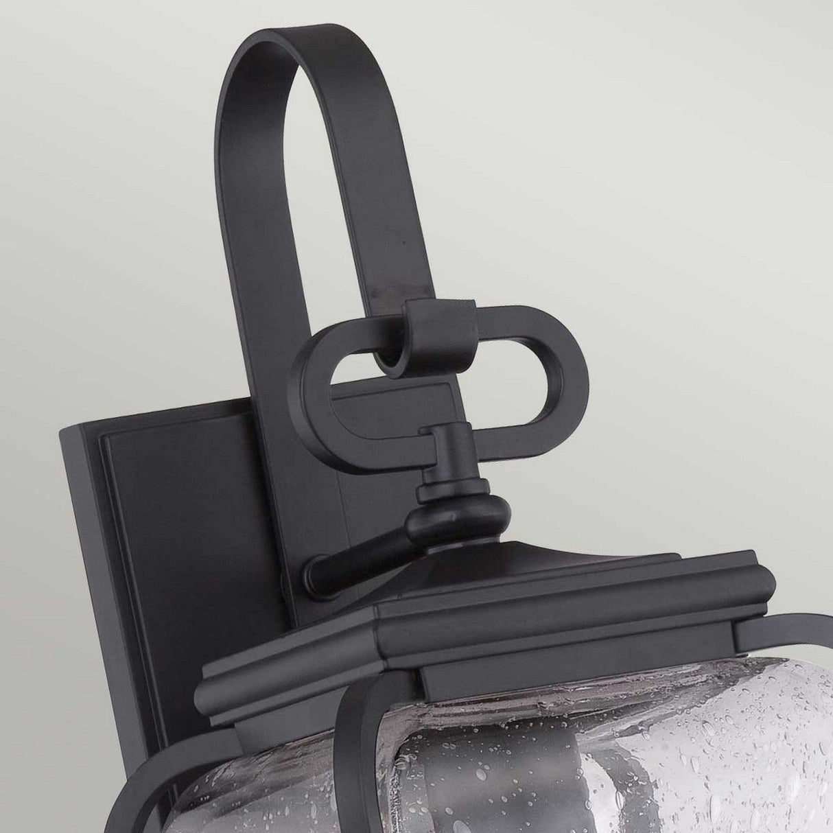 This close-up highlights the Province 1 Light Wall Lantern in black, expertly crafted from durable cast aluminum. It boasts a decorative curved handle and clear seeded glass, mounted on a flat rectangular base for a modern yet classic appeal.