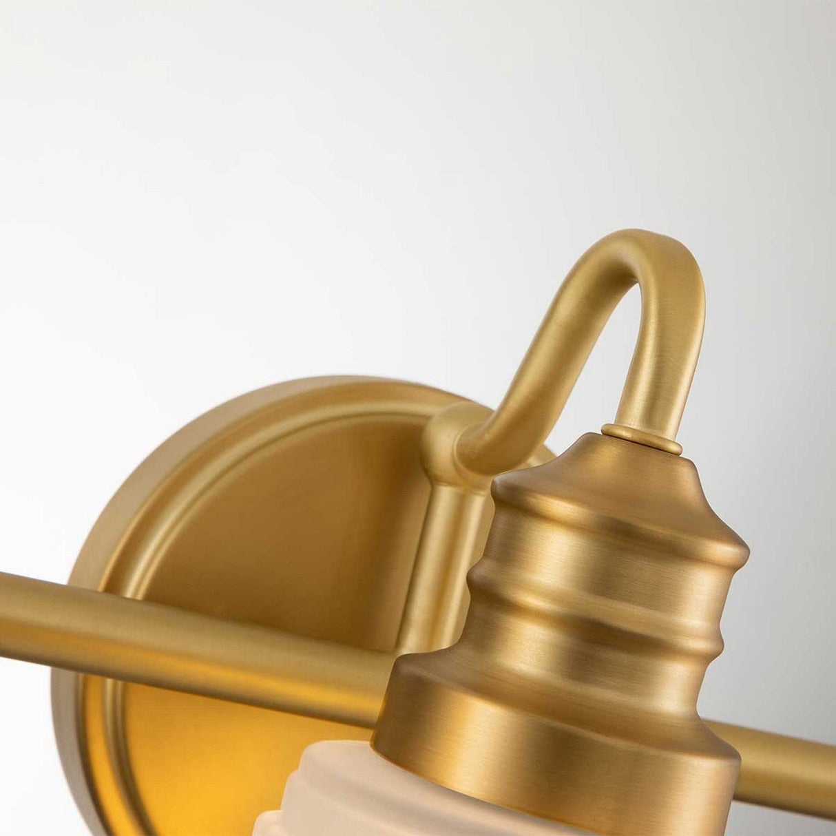 Close-up of the Swell 3 Light Wall Light - Brushed Brass showcasing its elegant curved arm and frosted glass shade, set against a plain white background. This fixture features a slightly brushed gold finish and is compatible with LED G9 bulbs, offering modern functionality along with a timeless design.