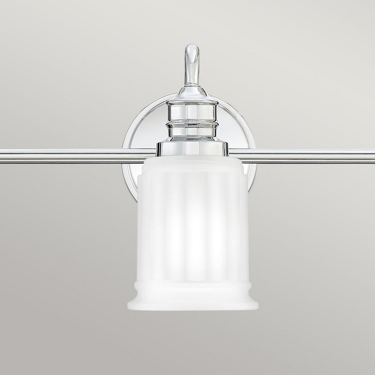 The Swell 3 Light Wall Light - Polished Chrome is a modern bathroom fixture featuring a frosted glass shade and a polished chrome base. Its sleek, cylindrical design with vertical grooves adds a contemporary aesthetic, making it ideal for enhancing bathroom vanities.