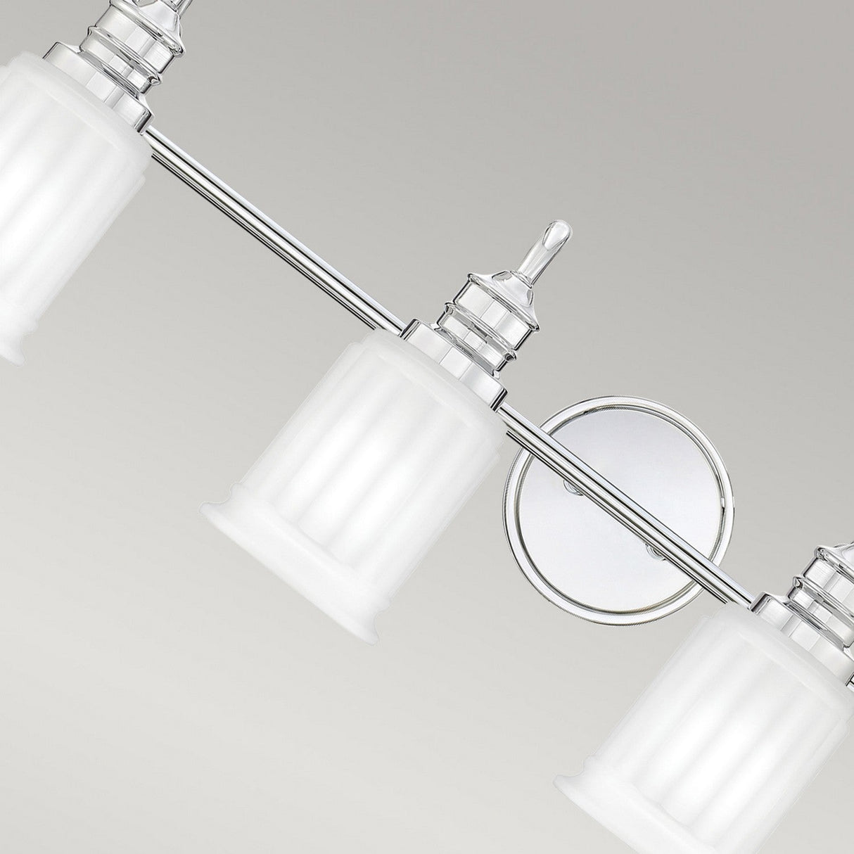 The Swell 4 Light Wall Light - Polished Chrome features three frosted glass shades mounted on a sleek, polished chrome wall bar against a neutral background. Ideal for bathroom lighting, its central circular attachment adds an elegant touch to the minimalist design, enhancing any modern home decor.