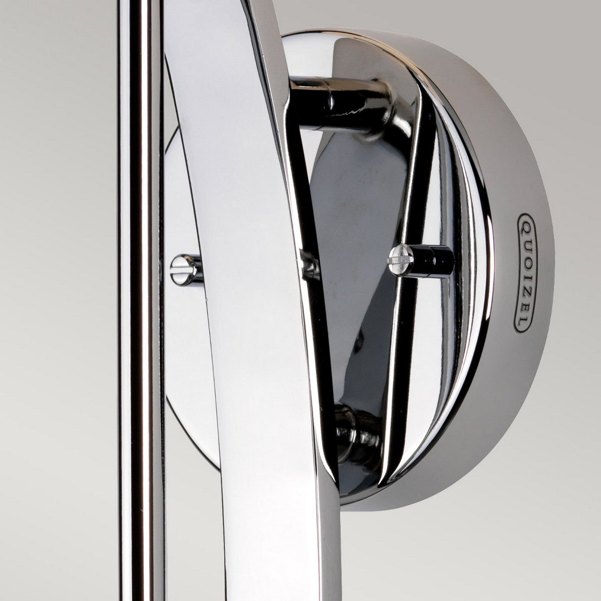 Close-up of the Taylor 1 Light Large Wall Light in polished chrome, showcasing a modern design with a circular base and two vertical bars. The name Quoizel is embossed on the base, complemented by an opal etched glass shade.