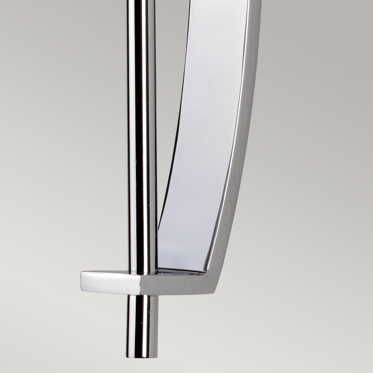 Close-up of the Taylor 1 Light Large Wall Light in polished chrome, showcasing its modern design with a sleek, curved aesthetic. The piece features a vertical rod and an elegantly curved element, set against a light gray background.