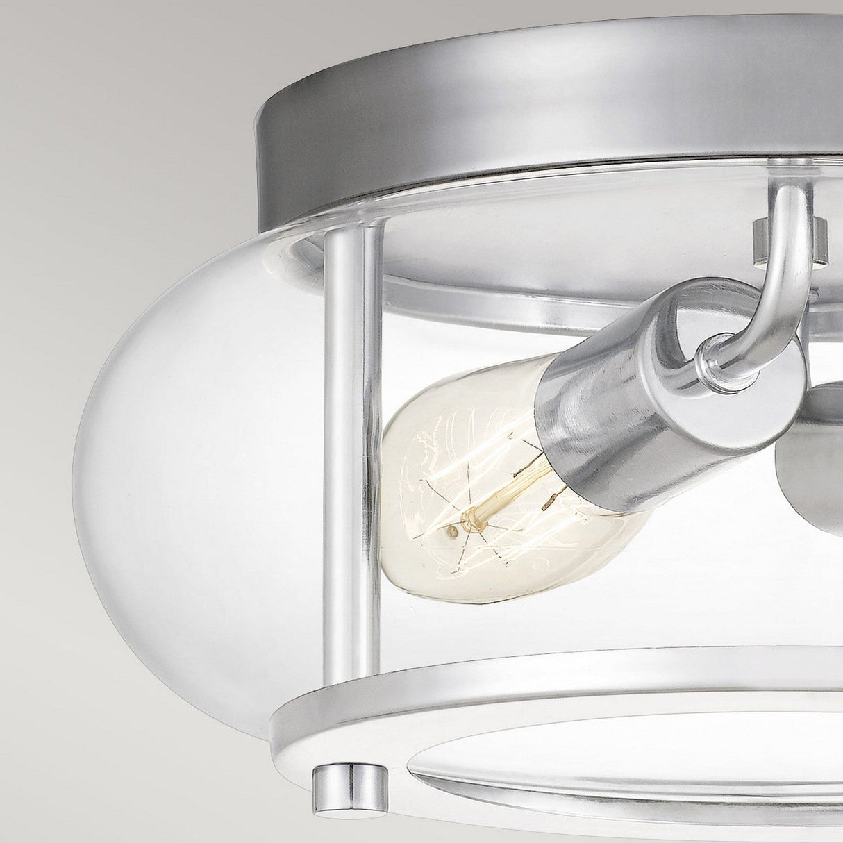 Introducing the Trilogy 2 Light Flush in Polished Chrome, a stylish flush mount light fixture that boasts a clear glass cover and an exposed bulb. This elegant design offers a contemporary look that enhances any plain background.