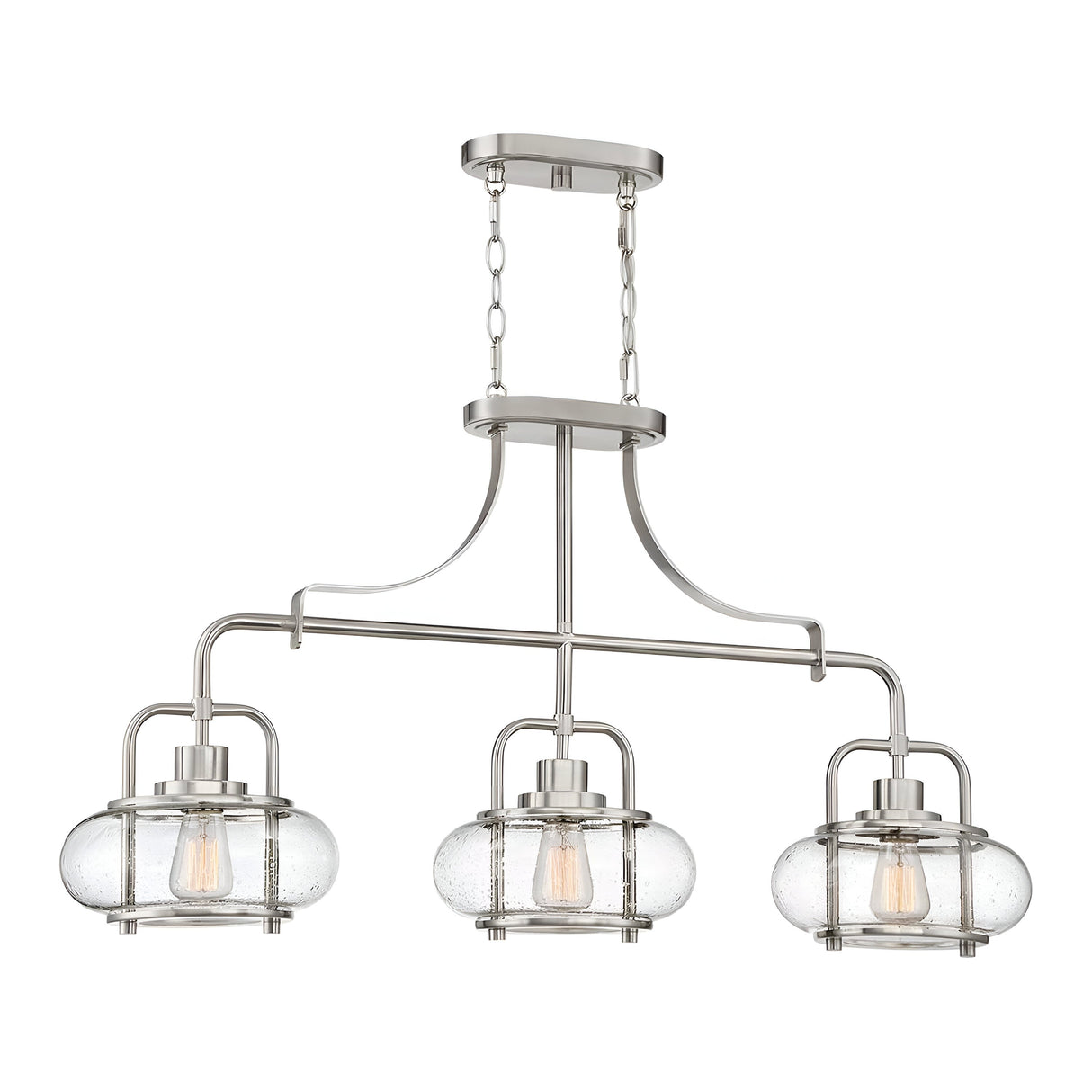 The Trilogy 3 Light Island Light in brushed nickel features three clear glass lanterns with exposed bulbs. Its sleek metallic frame, suspended by a chain, delivers a contemporary and elegant design, complemented by the sophisticated touch of seeded glass shades.