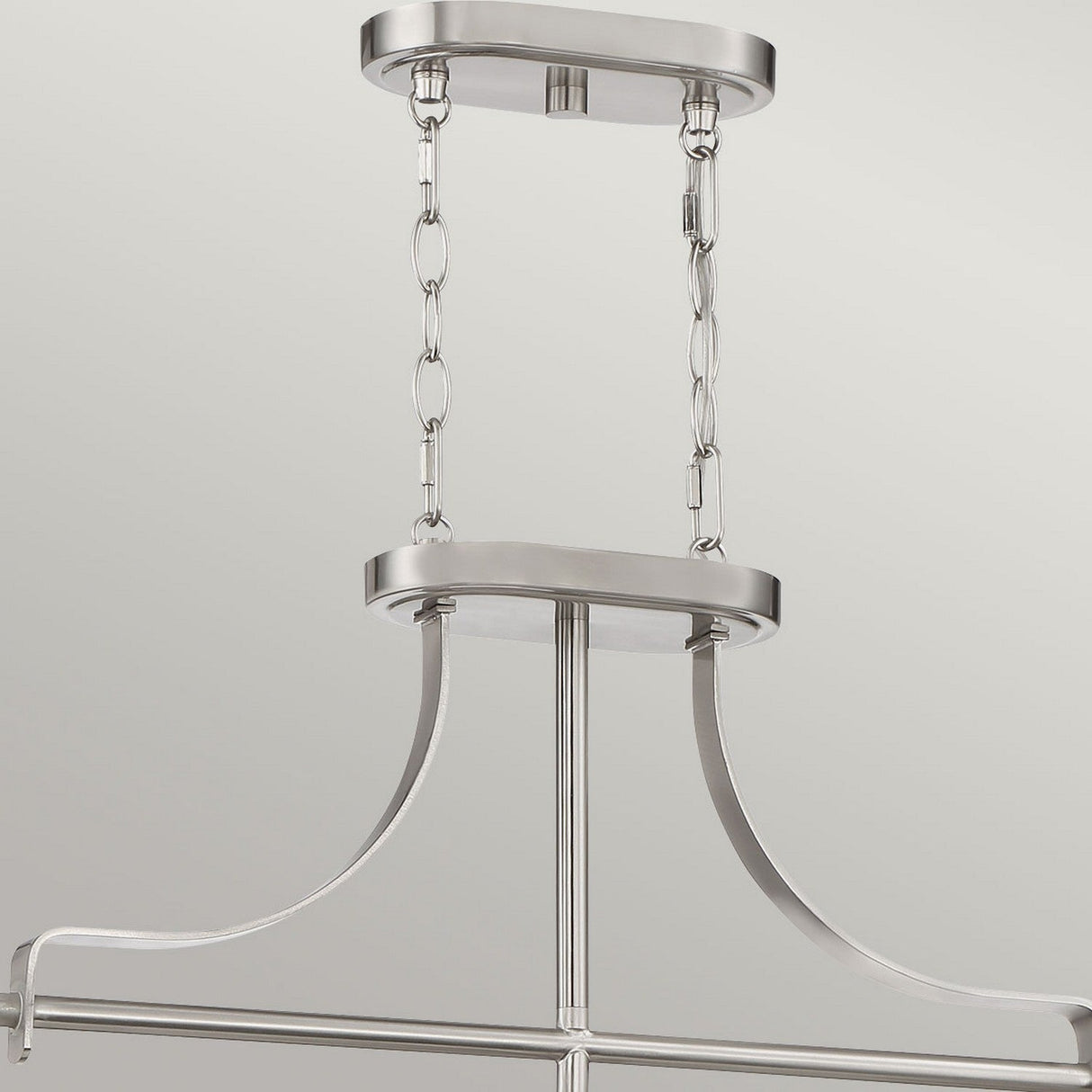 A close-up view of the Trilogy 3 Light Island Light in brushed nickel, showcasing its modern and sleek design with curved metal bars and chain links for mounting, set against a plain background. This elegant fixture epitomizes sophisticated simplicity.