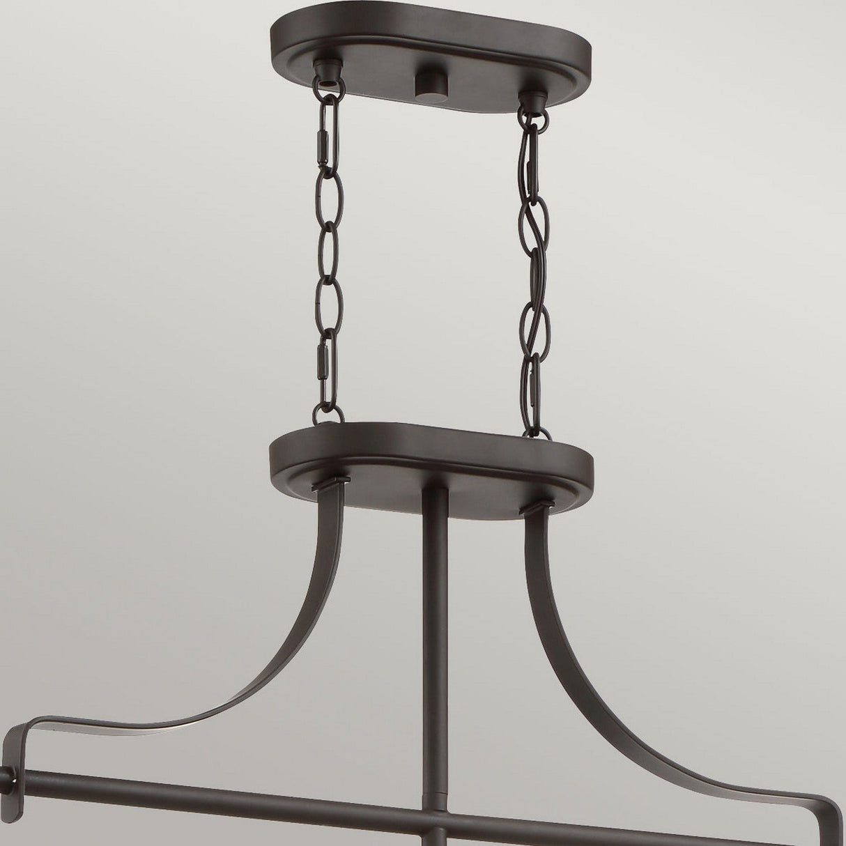 A close-up view of the Trilogy 3 Light Island Light - Olde Bronze reveals a modern metal chandelier with LED filament bulbs, supported by two chains attached to a rectangular ceiling mount. Its smooth, curved arms extend downward, connecting to the main fixture below. This industrial lighting piece boasts an Olde Bronze charm with its dark, matte finish.