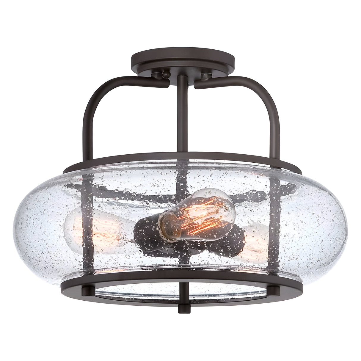 The Trilogy 3 Light Medium Semi-Flush in Old Bronze features a circular, seeded glass shade with a subtle bubbled texture. It houses three exposed filament bulbs within an old bronze metal frame, embodying the essence of industrial lighting.