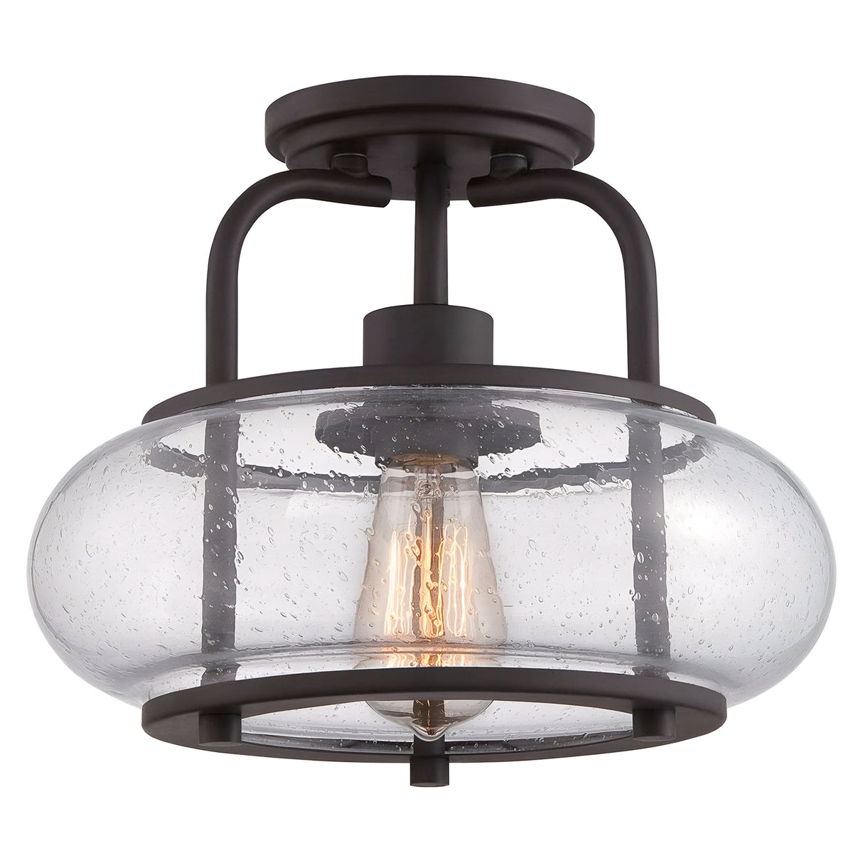 The Trilogy 1 Light Small Semi-Flush features an old bronze finish with a clear seeded glass shade. It includes a vintage-style Edison LED filament bulb, adding both an industrial and contemporary touch to its design.