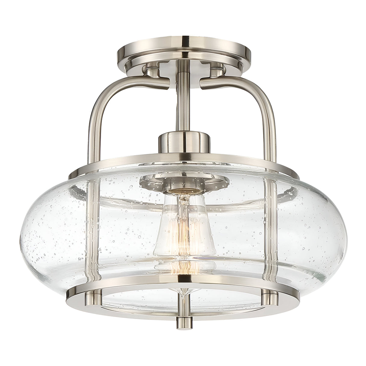 The Trilogy 1 Light Semi-Flush - Brushed Nickel is a modern ceiling light fixture that boasts a clear seeded glass shade encasing an Edison-style LED filament bulb. With its sleek curved metal supports and circular mount, it adds elegance to any room.