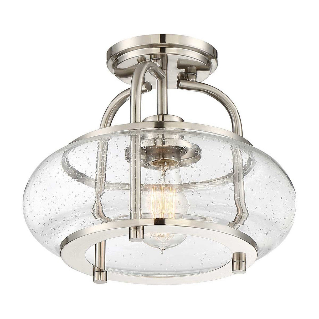 Introducing the Trilogy 1 Light Semi-Flush in Brushed Nickel: This ceiling light fixture showcases a clear, seeded glass shade accented by a metallic frame. It features an Edison-style LED filament bulb and boasts a sleek, modern design with its brushed nickel finish.