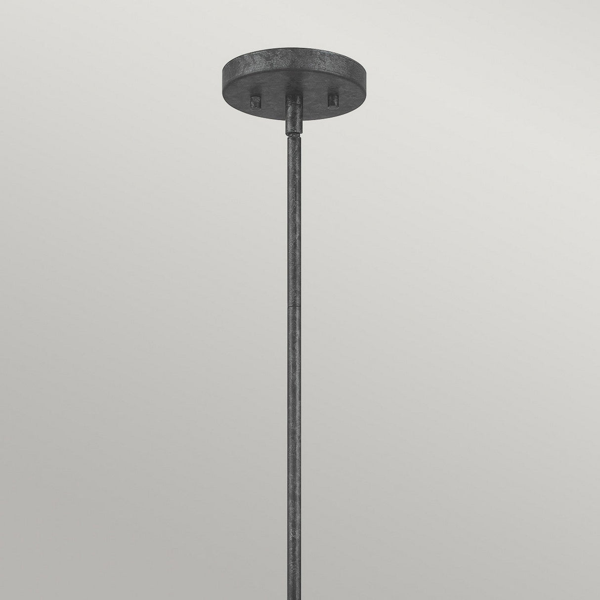 The Vanguard 4 Light Chandelier in Old Black, featuring a minimalist design with a round metal canopy and straight rod, effortlessly embodies industrial inspiration against a light grey backdrop.