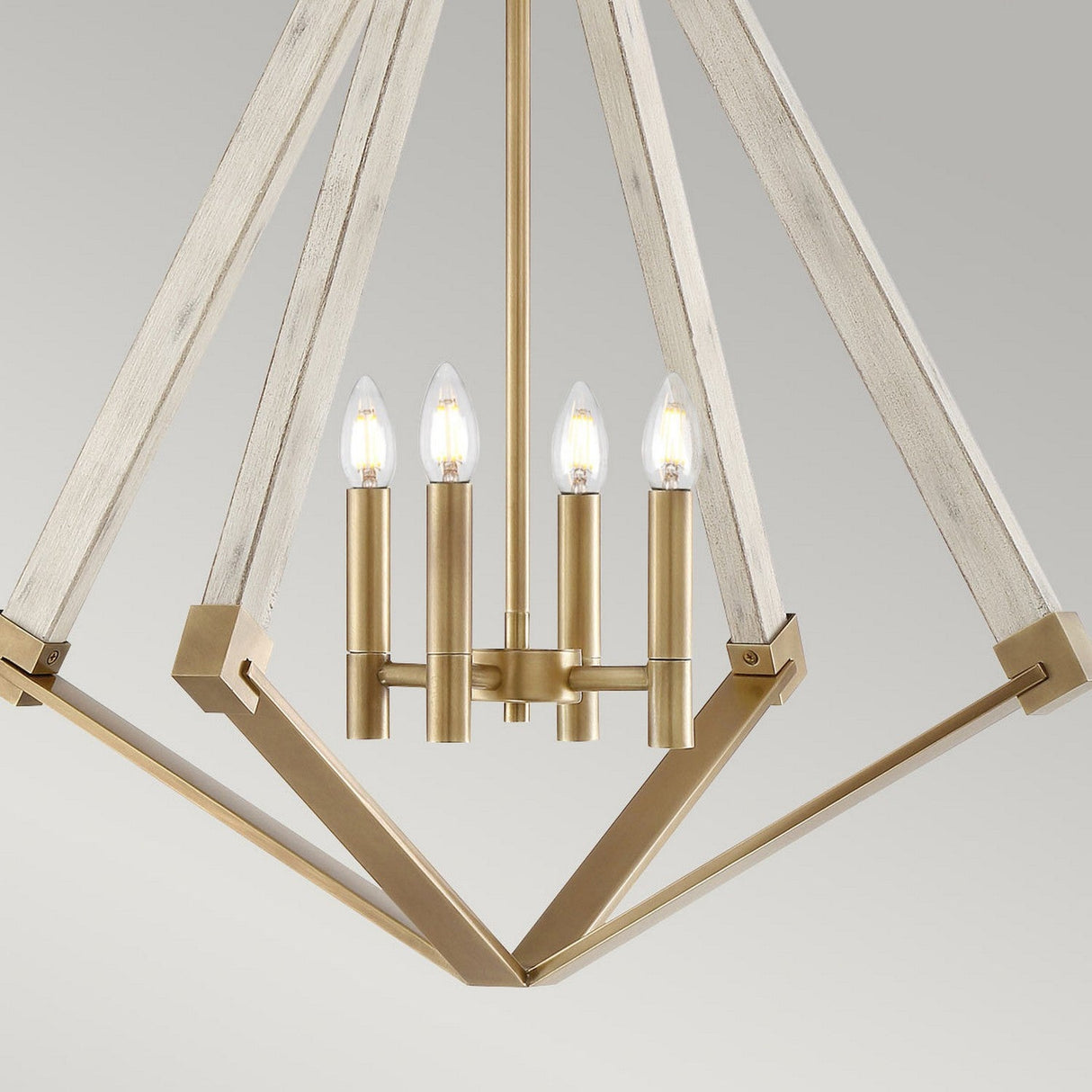 The View Point 4 Light Chandelier features a modern geometric design with a weathered brass frame and rustic wooden accents. It showcases four candle-style light bulbs arranged in a circular pattern, highlighted by a subtle whitewash wood effect against a neutral gray background.