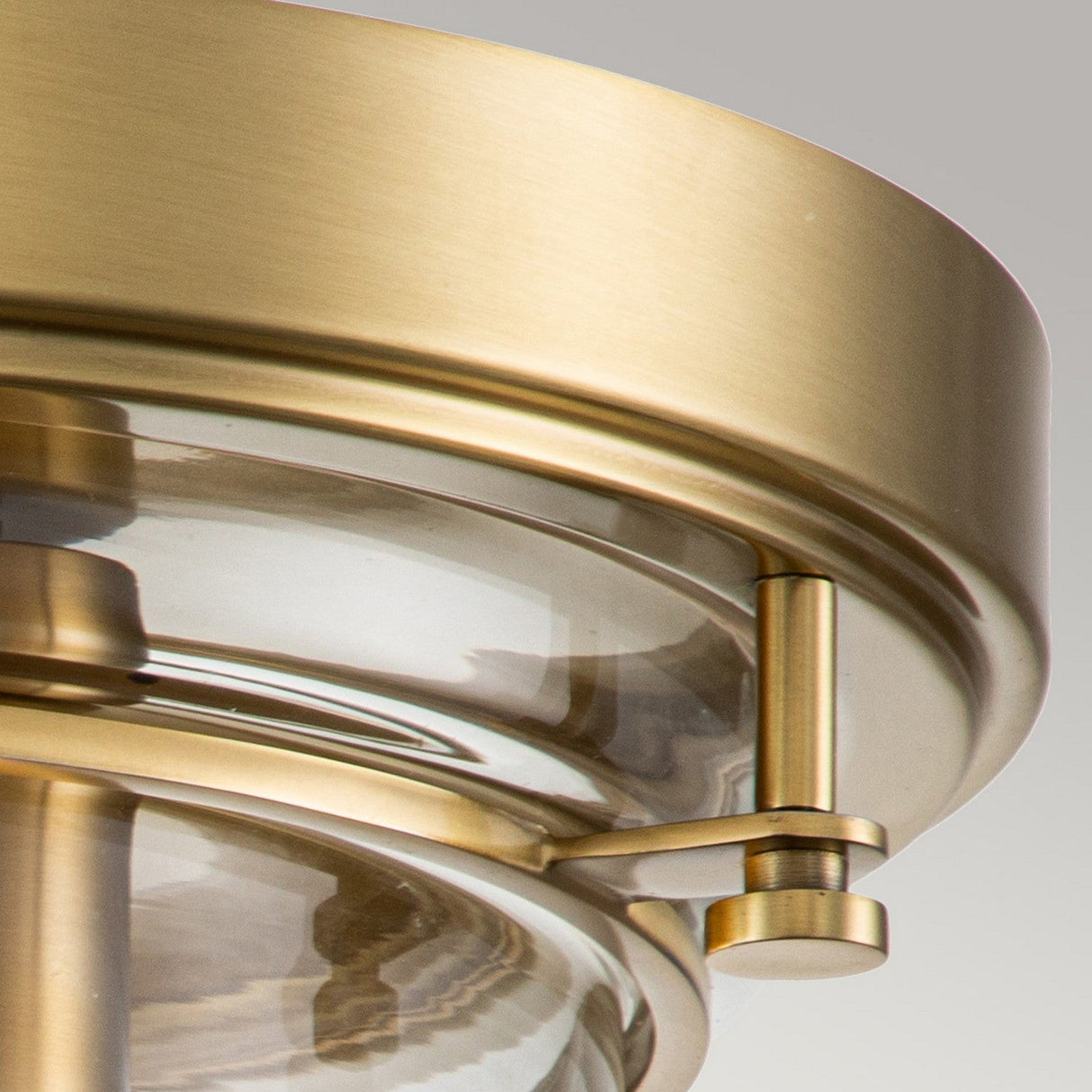 Here is an image of the Whistling 3 Light Flush in Brushed Brass, featuring a sleek and modern design with a circular brass frame that encases a clear glass cover. This IP44-rated fixture combines its brushed metal finish with a minimalistic style, effortlessly enhancing any space's elegance against a neutral backdrop.