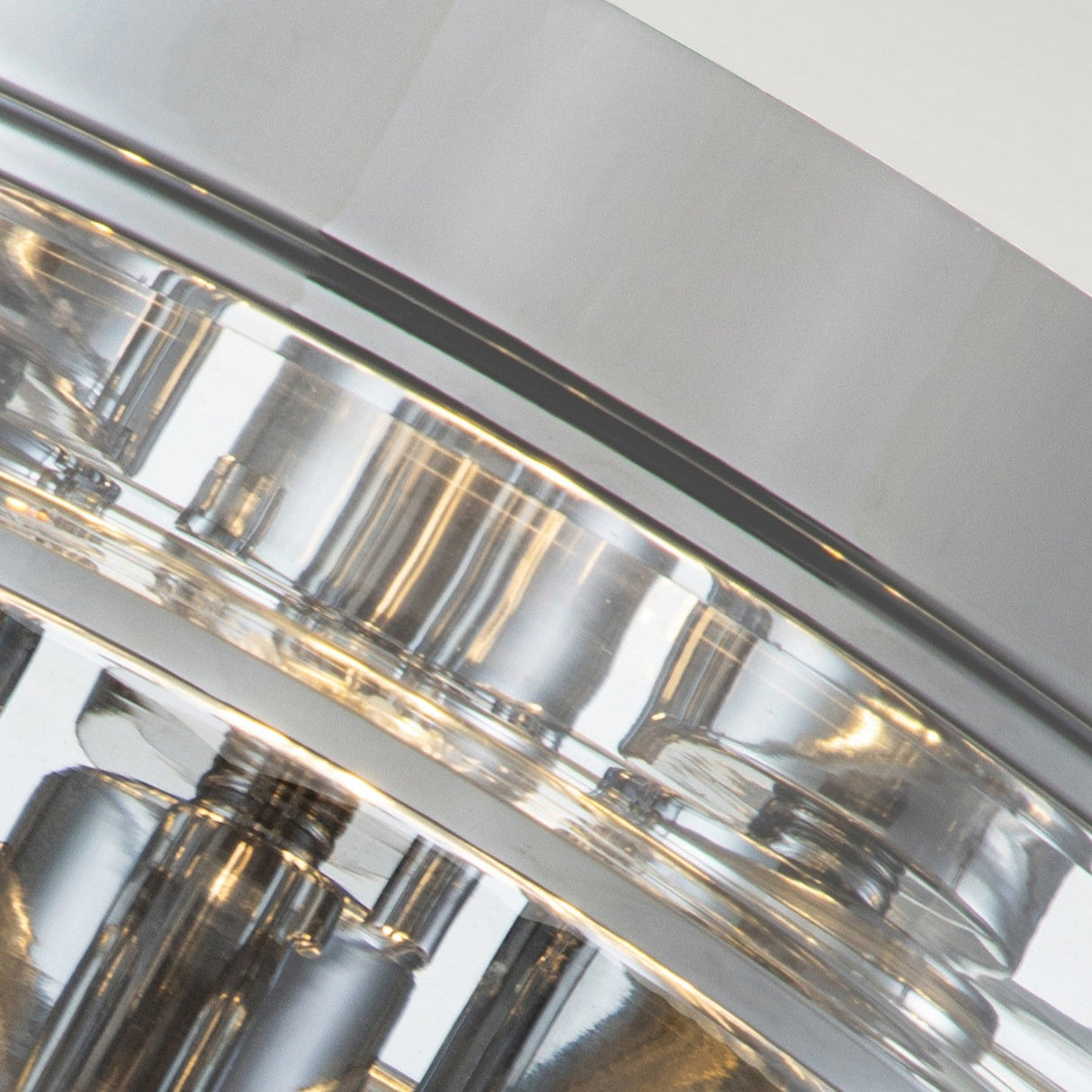 Close-up of a metallic object, likely part of bathroom lighting, with reflective surfaces and intricate details. The image emphasizes the polished chrome finish and geometric patterns of the Whistling 3 Light Flush - Polished Chrome, embodying a modern aesthetic.