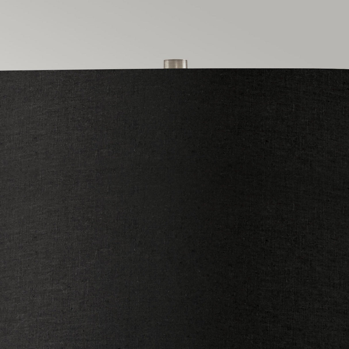 Close-up of the Ripple 1 Light Table Lamp featuring a sleek black shade and a small metallic finial on top, perfectly complementing its black base. This piece epitomizes contemporary lighting against the backdrop of a light gray wall, showcasing minimalist design at its finest.