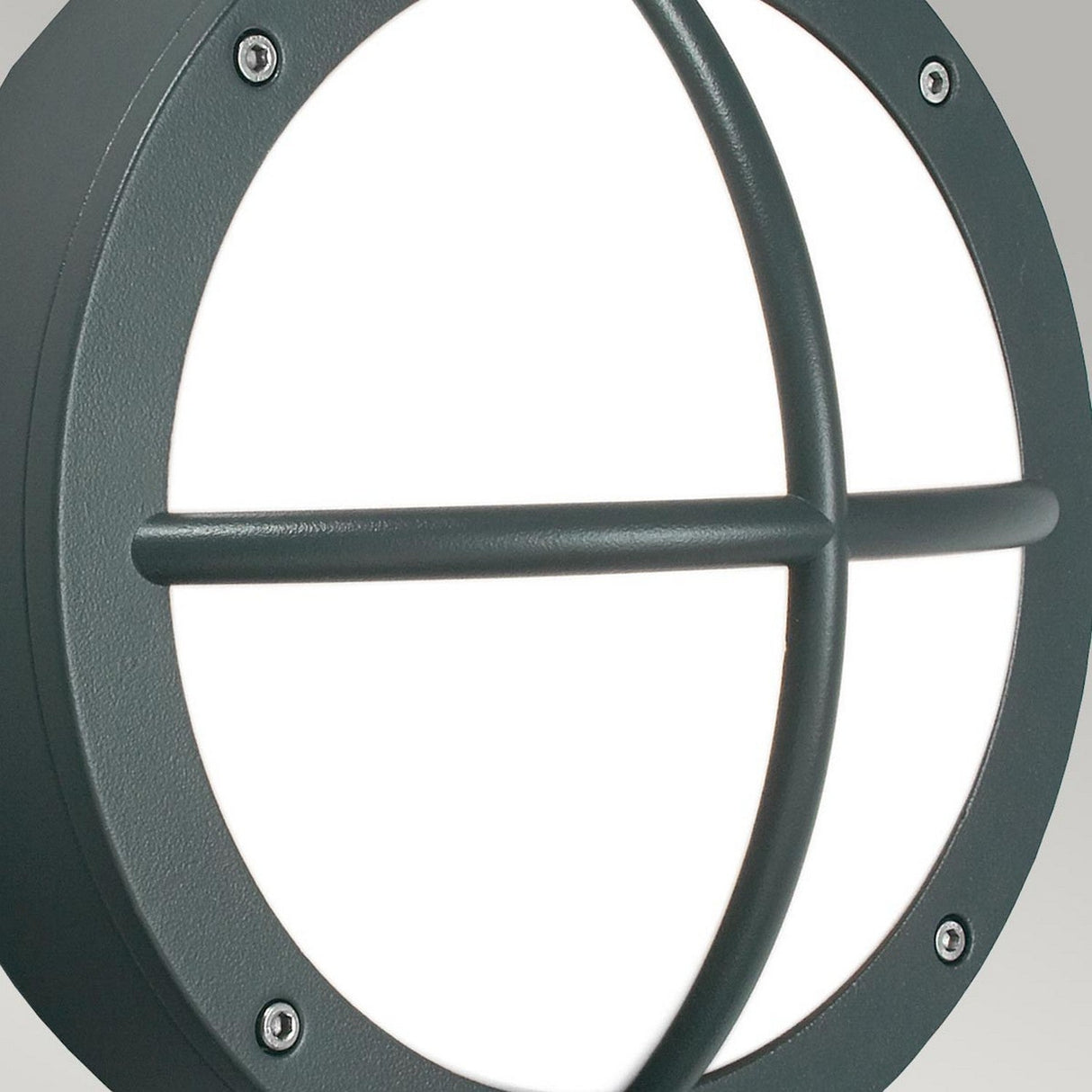 A close-up of the Rondane Outdoor LED Wall Light in graphite showcases its round design with a sturdy black metal frame and crossbar over frosted white glass. This energy-efficient light, rated IP65 for outdoor resilience, is firmly secured with four screws to endure various weather conditions.