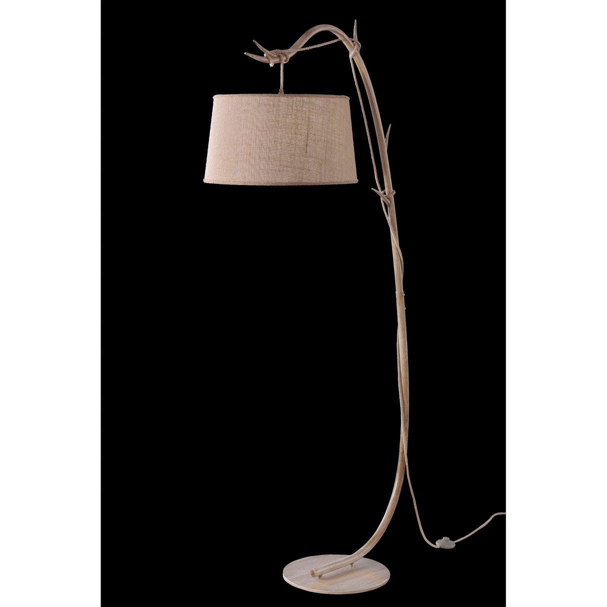 The Sabina 1 Light Floor Lamp features a curved, brown wood-like stem, round base, and a linen shade, adding rustic charm to bohemian spaces—ideal for accenting décor against a bold black background.