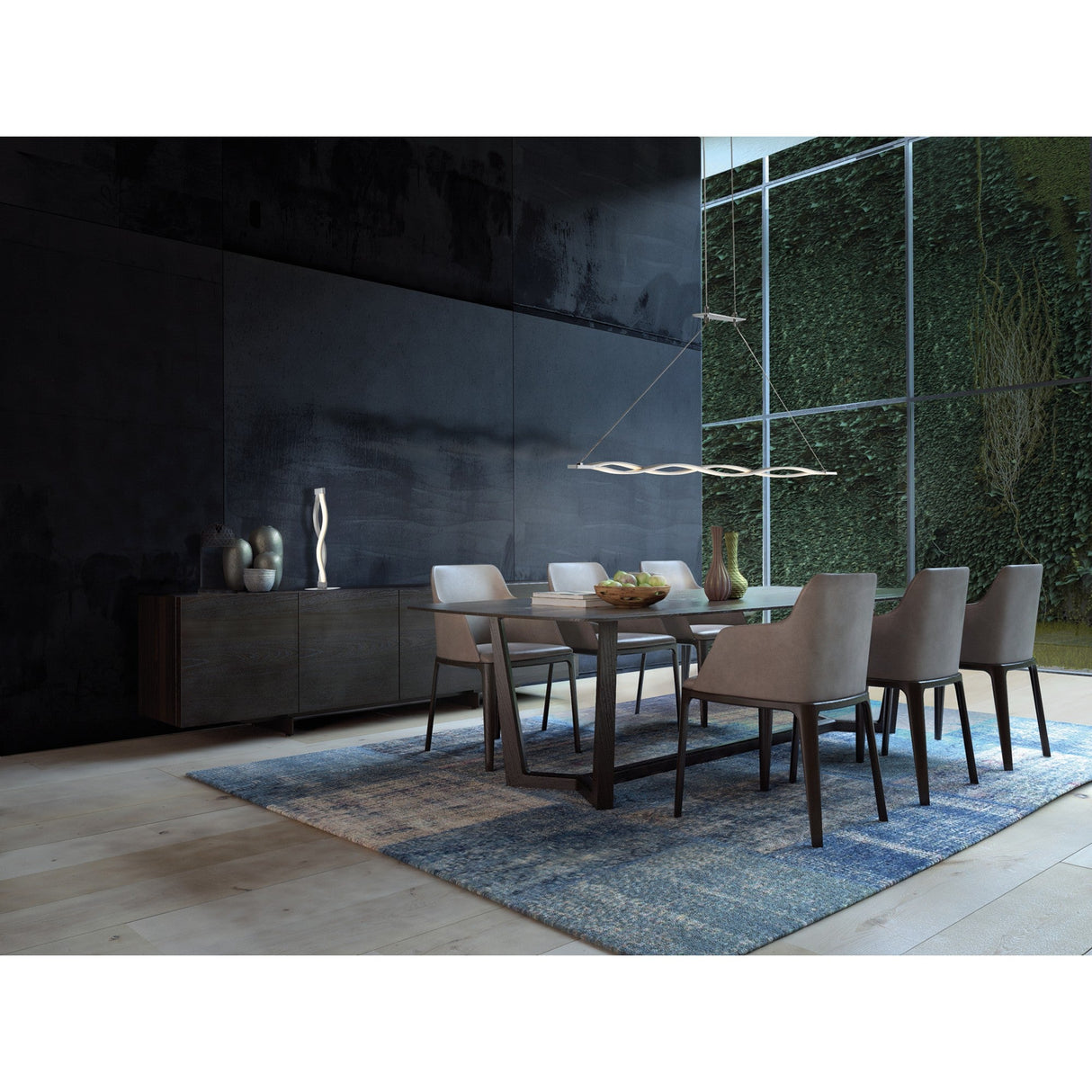 A modern dining room with a rectangular table, six upholstered chairs, the Sahara LED Table Lamp 6W 3000K - Silver & Chrome for energy-efficient lighting, a blue rug, sideboard with vases, dark walls, and large windows overlooking a plant-covered wall.