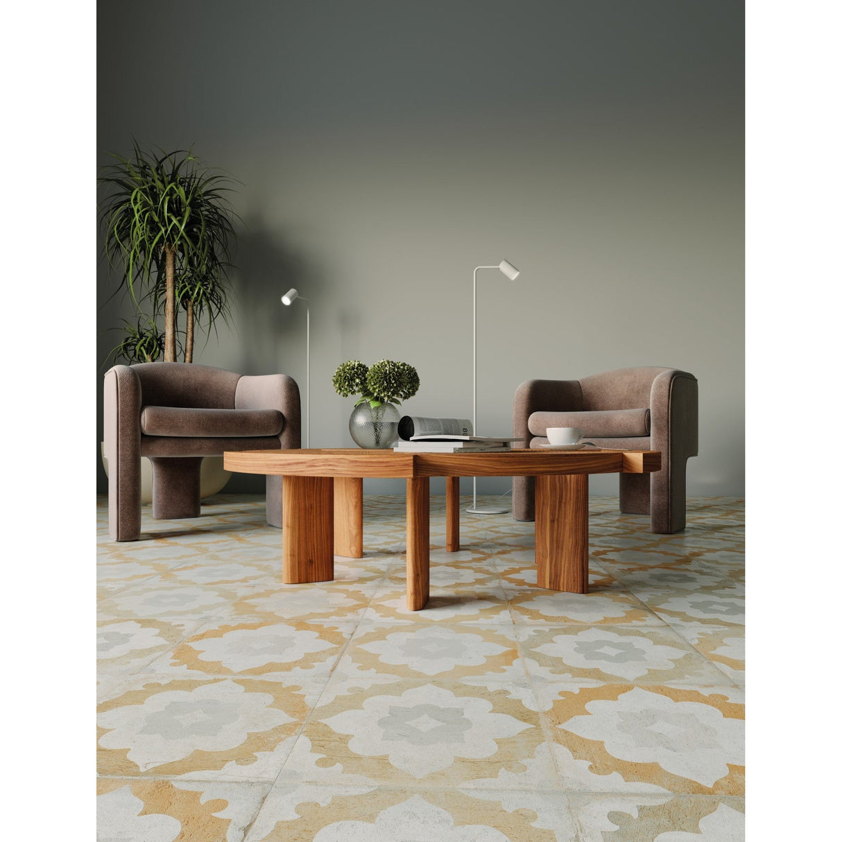 A modern living room with two taupe armchairs, a wooden coffee table decorated with plants and books, a tall potted plant, patterned tile flooring, and two Sal 1 Light Floor Lamps in matt white featuring adjustable spotlights.