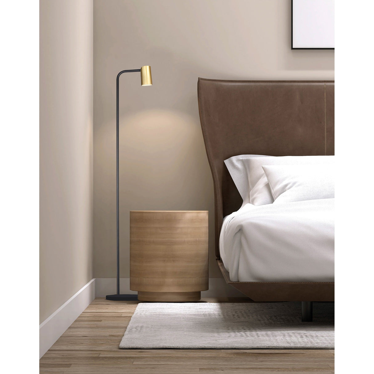 Modern bedroom corner with a leather-upholstered bed, white bedding, a round wooden nightstand, and the contemporary Sal 1 Light Floor Lamp in satin gold and matt black. Light walls and a soft rug enhance the warm wooden flooring for a cozy atmosphere.