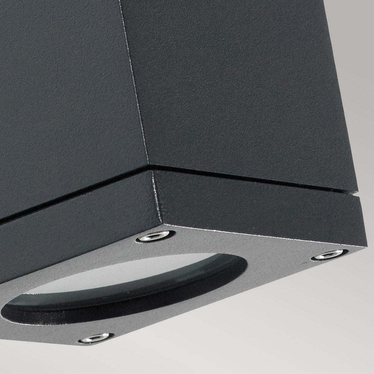Close-up of a Sandvik Outdoor 1 Light Down Wall Light in graphite, showcasing its rectangular shape with a round opening and four corner screws, set against a light gray background.
