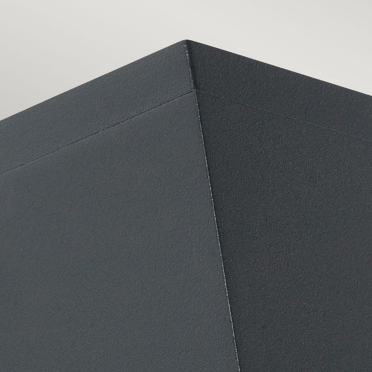 Close-up image of a geometric, dark gray Sandvik Outdoor 1 Light Down Wall Light with sharp, clean edges, set against a light gray background. The focus is on the corner of the wall light, showcasing its graphite finish and accurate angles, echoing its IP65 rating.