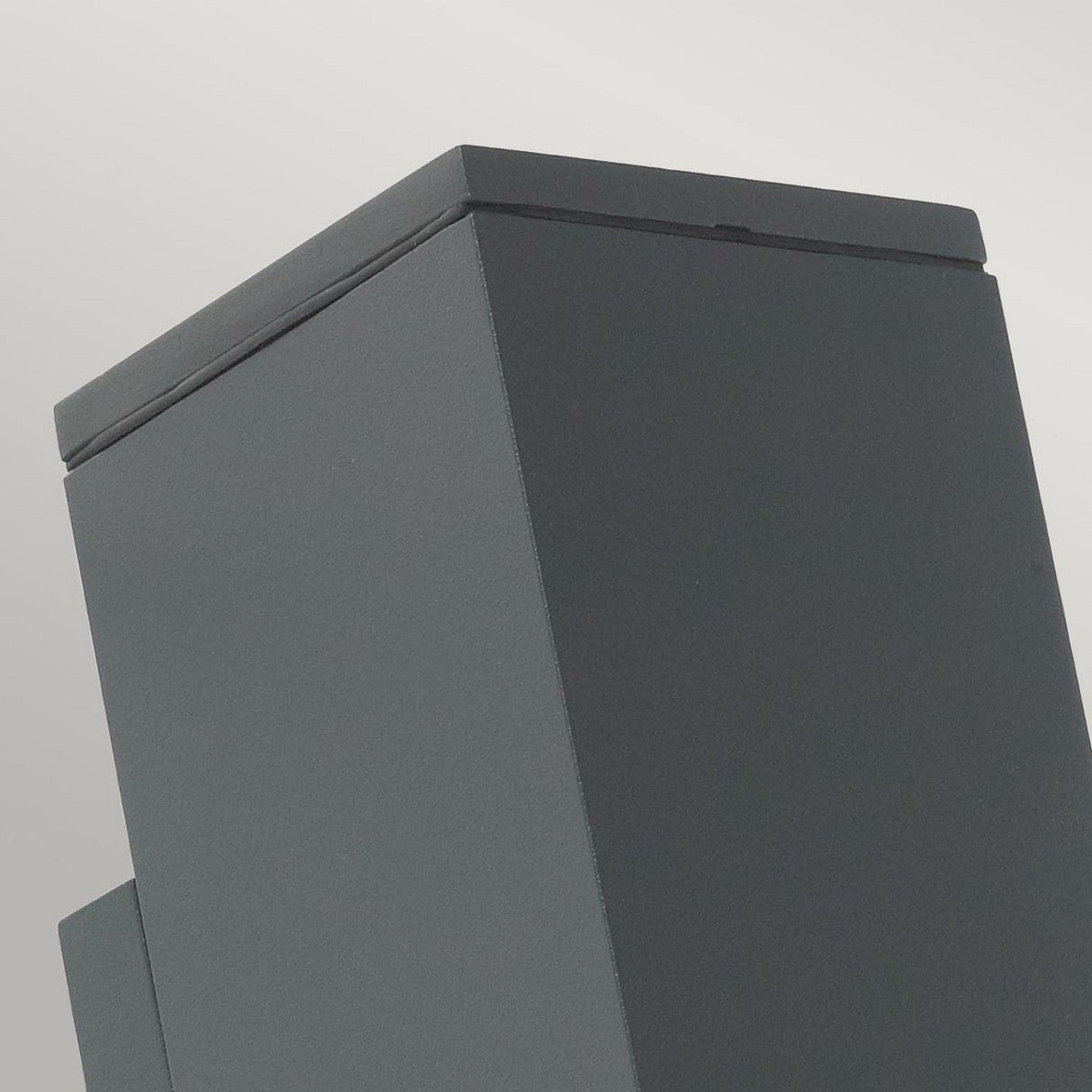 A close-up view showcases the Sandvik Outdoor 2 Light Up & Down Wall Light in graphite, designed with a modern rectangular column against a light gray background. The smooth surface and clean, angular lines reflect its minimalist style, while the IP65 rating emphasizes its outdoor suitability.