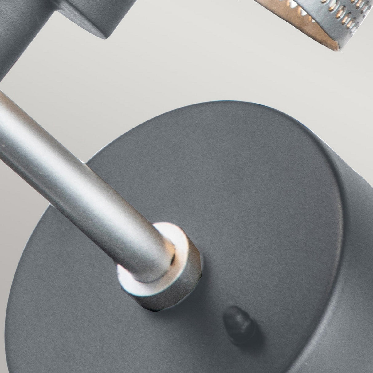 A close-up of the Saturne 1 Light Outdoor Wall Light showcases its metallic, cylindrical design attached to a round base. This fixture, with an IP44 rating and a silver mesh diffuser, exudes a sleek and modern aesthetic complemented by its grey finish against a neutral background.