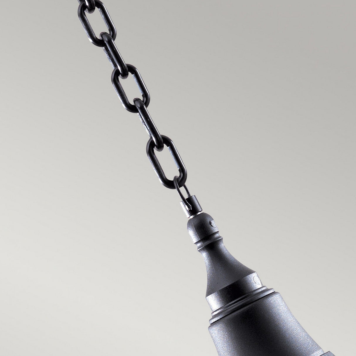 A close-up of the Shannon 1 Light Outdoor Chain Pendant in black, featuring a corrosion-proof polymer chain suspending the fixture against a gray background. The pendant boasts a sleek, modern design and an IP44 rating for durability.