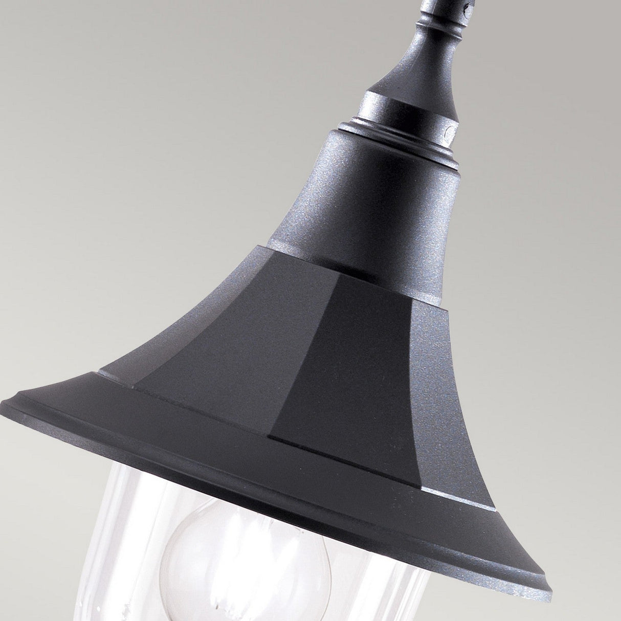 Close-up of the Shannon 1 Light Outdoor Chain Pendant in black, showcasing its classic, tapered design crafted from corrosion-proof black polymer. The light bulb is visible through the clear glass casing, while its IP44 rating ensures it withstands any weather. The background features a soft, neutral color.
